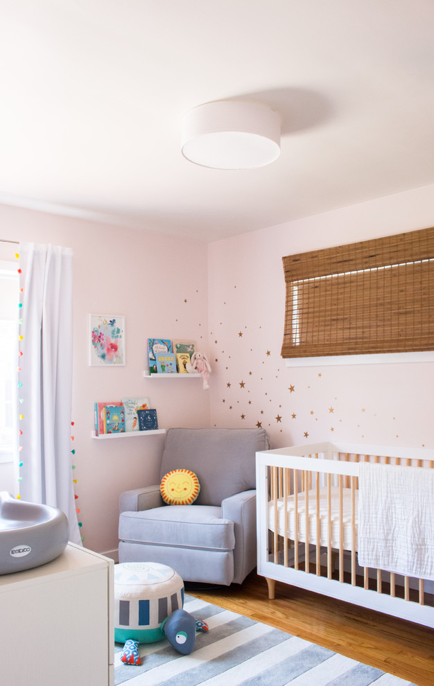 Inspiration for a small eclectic nursery for girls in Los Angeles with pink walls, light hardwood floors and yellow floor.