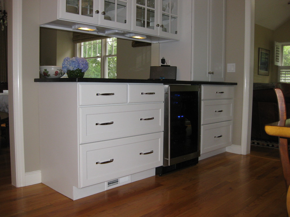 Transitional u-shaped medium tone wood floor eat-in kitchen photo in Boston with an undermount sink, recessed-panel cabinets, white cabinets, gray backsplash, subway tile backsplash, stainless steel appliances, an island and black countertops