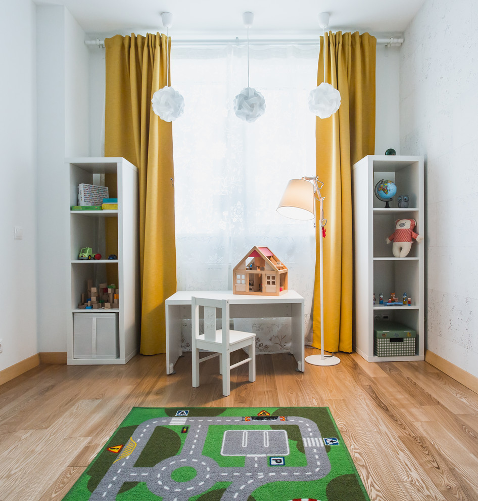 This is an example of a contemporary kids' room in Moscow with white walls and light hardwood floors.