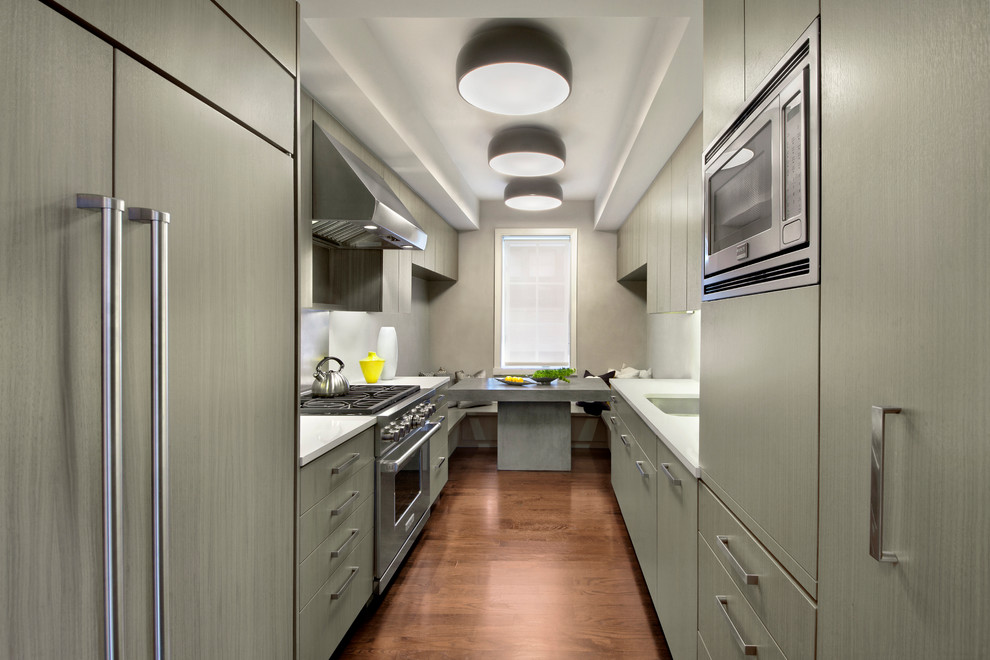 Photo of a small contemporary galley separate kitchen in New York with flat-panel cabinets, grey cabinets, stainless steel appliances, medium hardwood floors, an undermount sink, metallic splashback and no island.