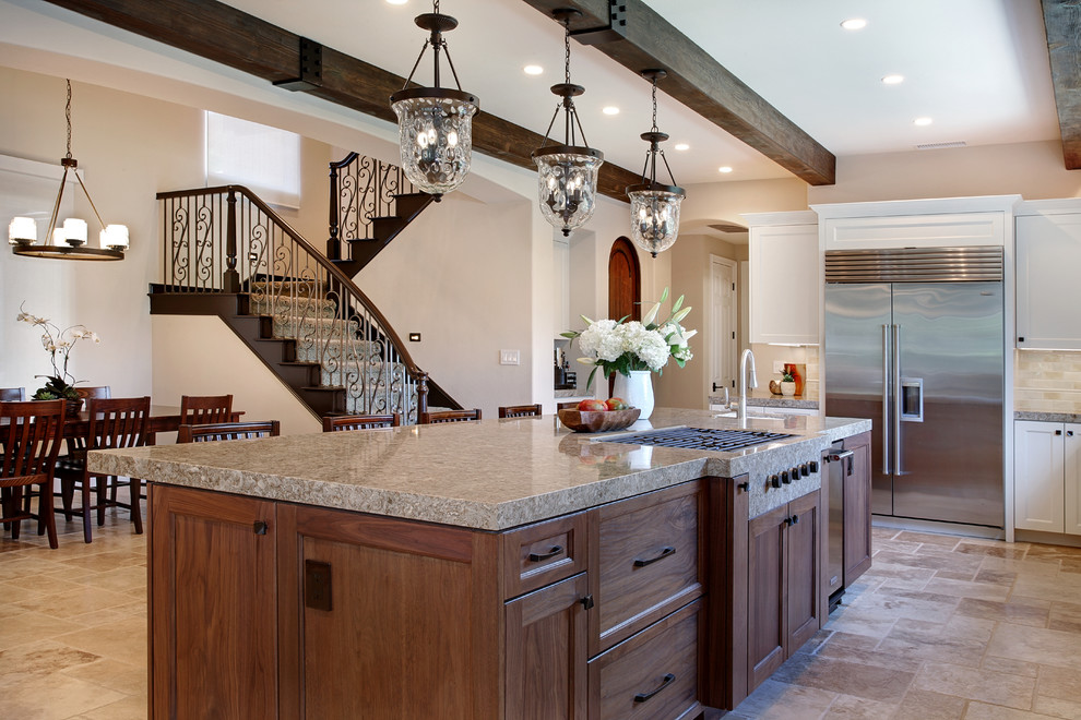 This is an example of an expansive mediterranean l-shaped eat-in kitchen in Orange County with a farmhouse sink, shaker cabinets, white cabinets, quartz benchtops, multi-coloured splashback, ceramic splashback, stainless steel appliances, travertine floors, with island and beige floor.