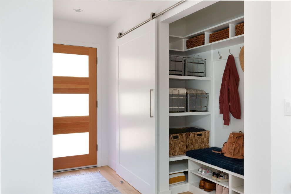 Example of a large transitional light wood floor and brown floor front door design with white walls and a medium wood front door