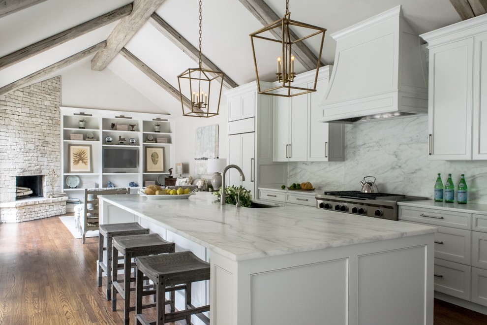 Design ideas for a traditional galley open plan kitchen in Austin with a single-bowl sink, recessed-panel cabinets, white cabinets, marble benchtops, white splashback, stone slab splashback, panelled appliances, medium hardwood floors and with island.