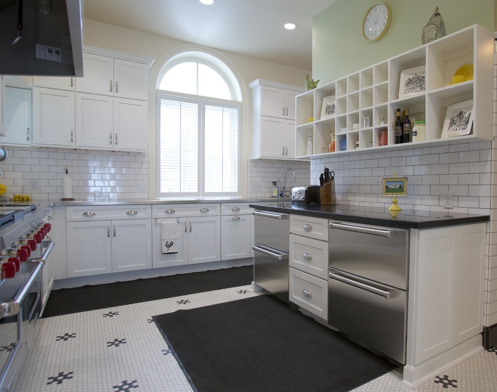 Large traditional kitchen in Milwaukee with a farmhouse sink, white cabinets, white splashback, subway tile splashback, stainless steel appliances and porcelain floors.