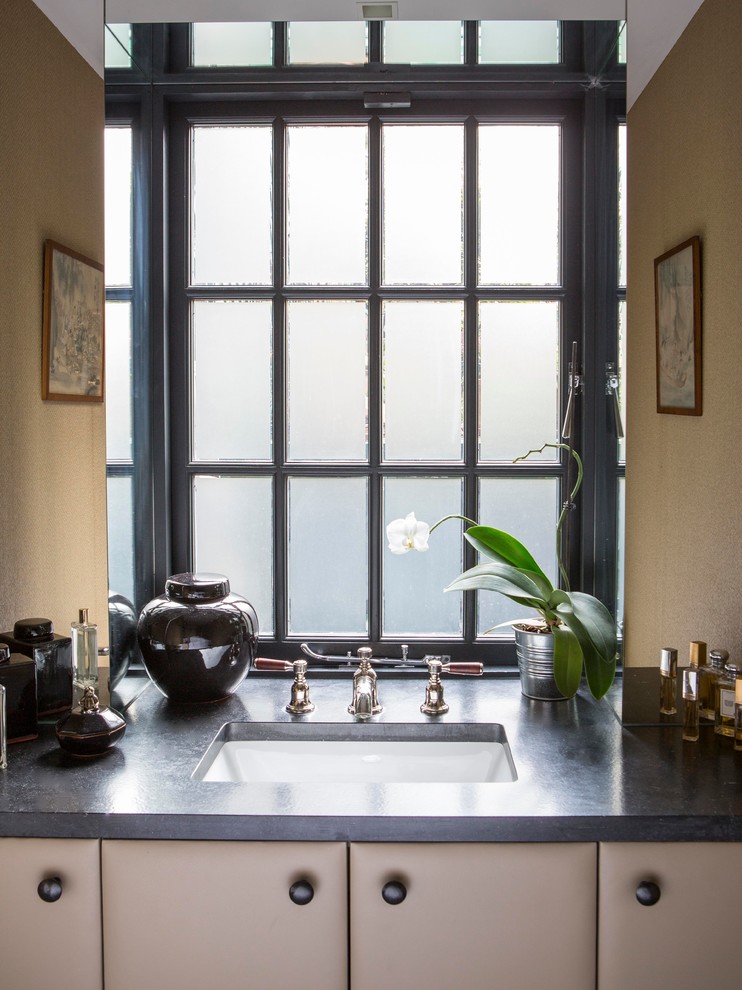 This is an example of a small contemporary powder room in London with an undermount sink, granite benchtops, yellow walls and porcelain floors.