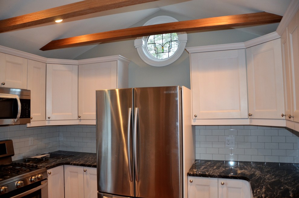 Inspiration for a small transitional medium tone wood floor enclosed kitchen remodel in Boston with an undermount sink, glass-front cabinets, granite countertops, white backsplash, ceramic backsplash and stainless steel appliances