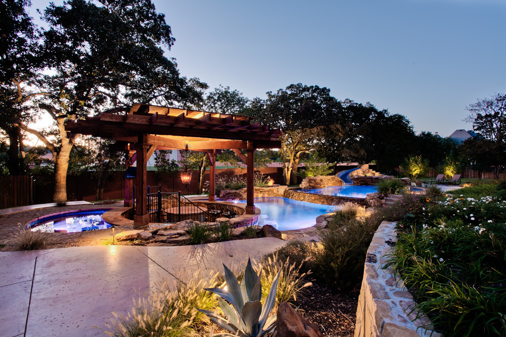 This is an example of an expansive tropical backyard full sun garden in Dallas with a water feature and natural stone pavers.