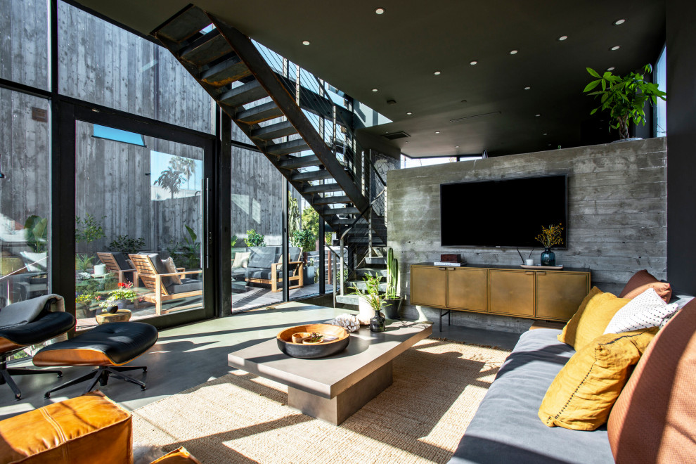 Mittelgroßes, Abgetrenntes Industrial Wohnzimmer ohne Kamin mit grauer Wandfarbe, Betonboden, TV-Wand und grauem Boden in Los Angeles