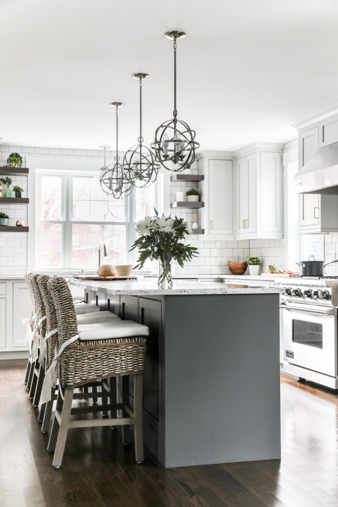 Transitional l-shaped eat-in kitchen in Boston with white cabinets, quartz benchtops, white splashback, subway tile splashback, stainless steel appliances, medium hardwood floors, with island, brown floor, grey benchtop and shaker cabinets.