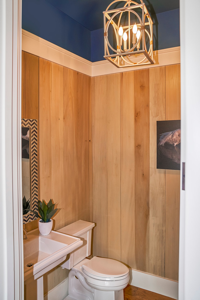 This is an example of a small transitional powder room in Charleston with a one-piece toilet, brown walls, medium hardwood floors and a pedestal sink.