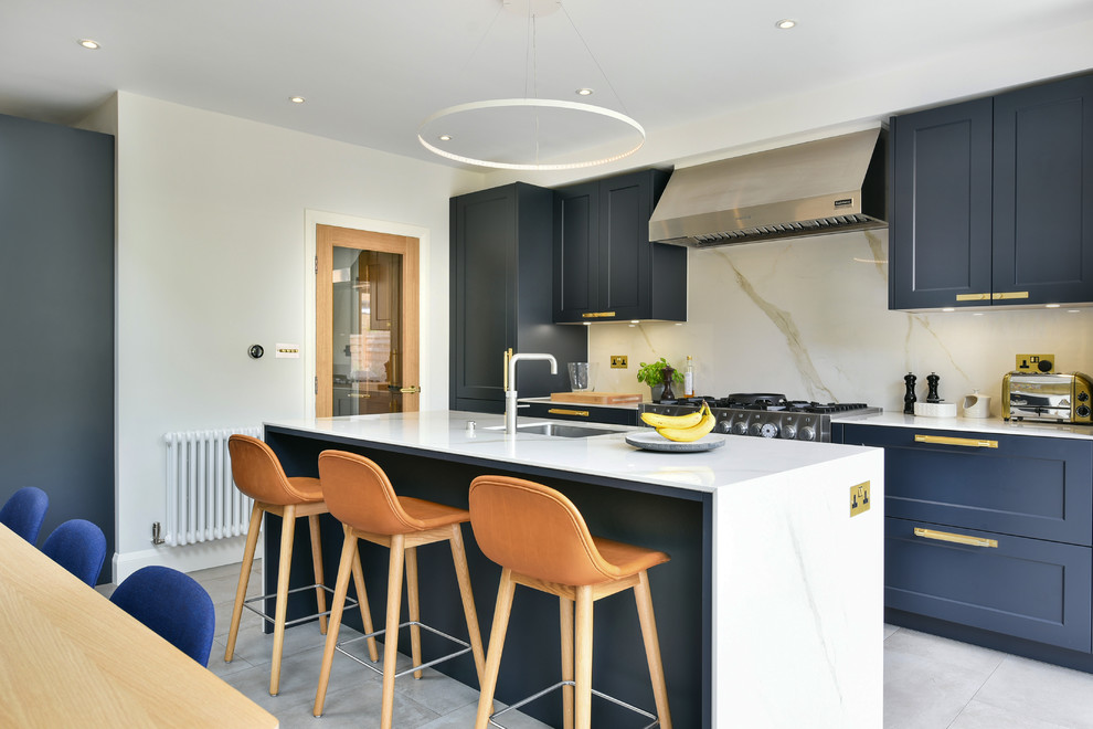 Inspiration for a contemporary galley eat-in kitchen in London with an undermount sink, shaker cabinets, blue cabinets, stone slab splashback, with island, grey floor and white benchtop.