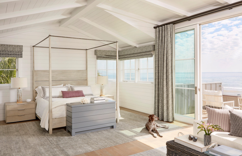 Photo of a beach style bedroom in Santa Barbara with white walls, medium hardwood floors, brown floor, exposed beam, timber, vaulted and planked wall panelling.