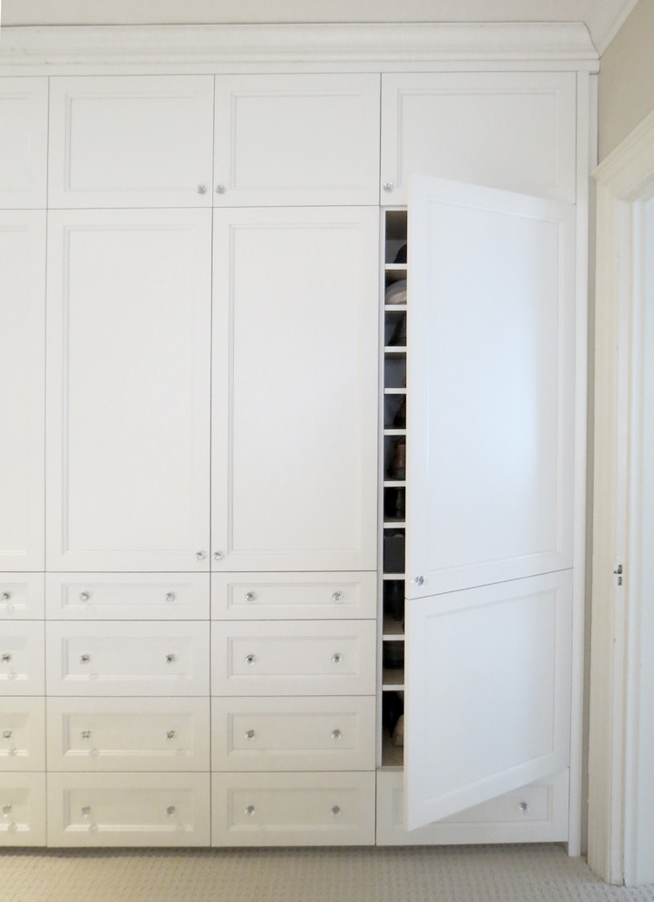 This is an example of a small transitional gender-neutral built-in wardrobe in Toronto with recessed-panel cabinets, white cabinets and carpet.