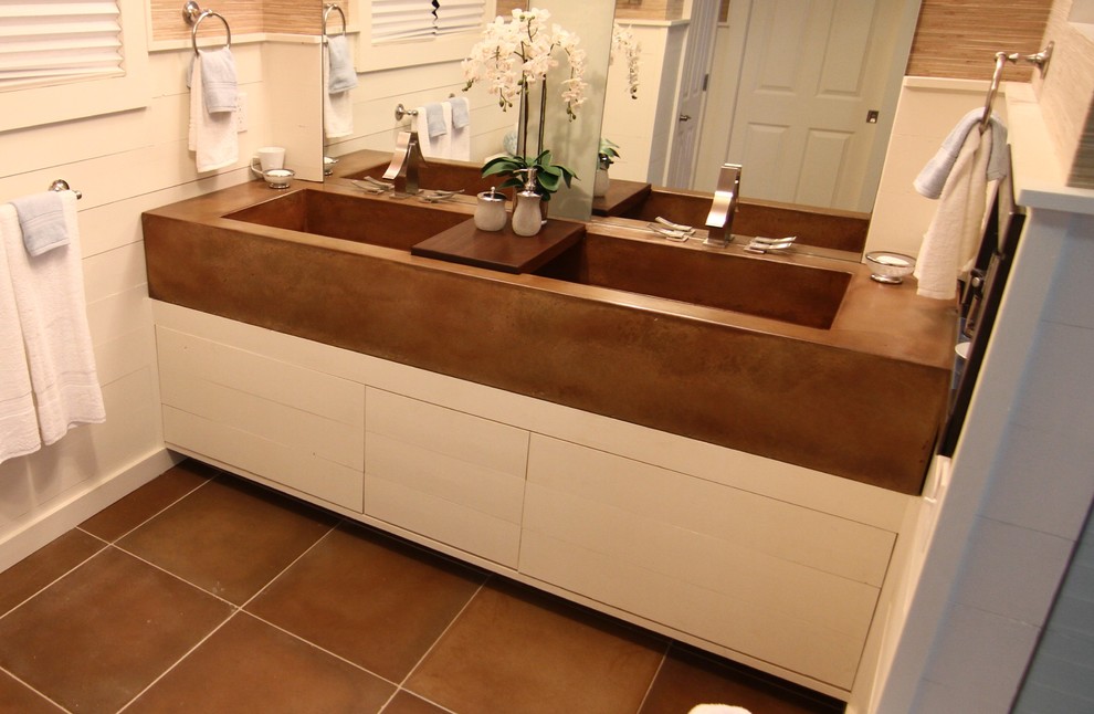 Photo of a mid-sized master bathroom in Minneapolis with a trough sink, flat-panel cabinets, white cabinets, concrete benchtops, a curbless shower, a one-piece toilet, brown tile, glass sheet wall, beige walls and concrete floors.