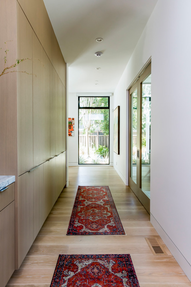 Ispirazione per un grande ingresso o corridoio design con pareti bianche, parquet chiaro e pavimento marrone