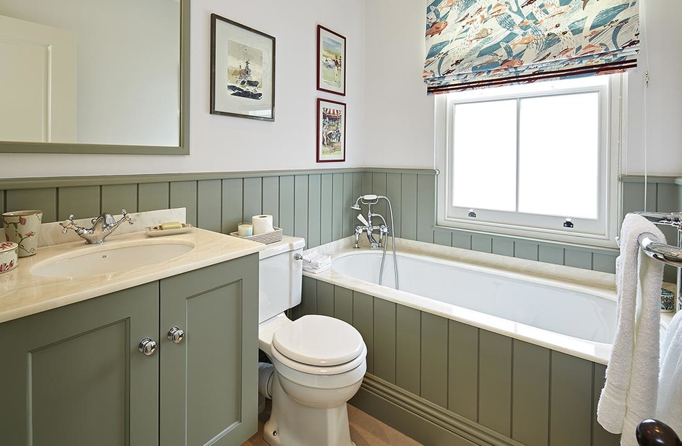 Inspiration for a small traditional kids bathroom in London with recessed-panel cabinets, green cabinets, an alcove tub, a shower/bathtub combo, a one-piece toilet, multi-coloured tile, beige walls, an undermount sink, marble benchtops, brown floor and an open shower.