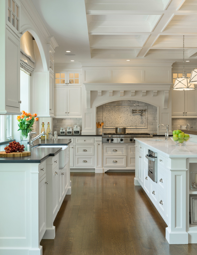 Photo of a traditional kitchen in Boston with beaded inset cabinets, white cabinets, white splashback, subway tile splashback, dark hardwood floors, with island, a farmhouse sink and stainless steel appliances.