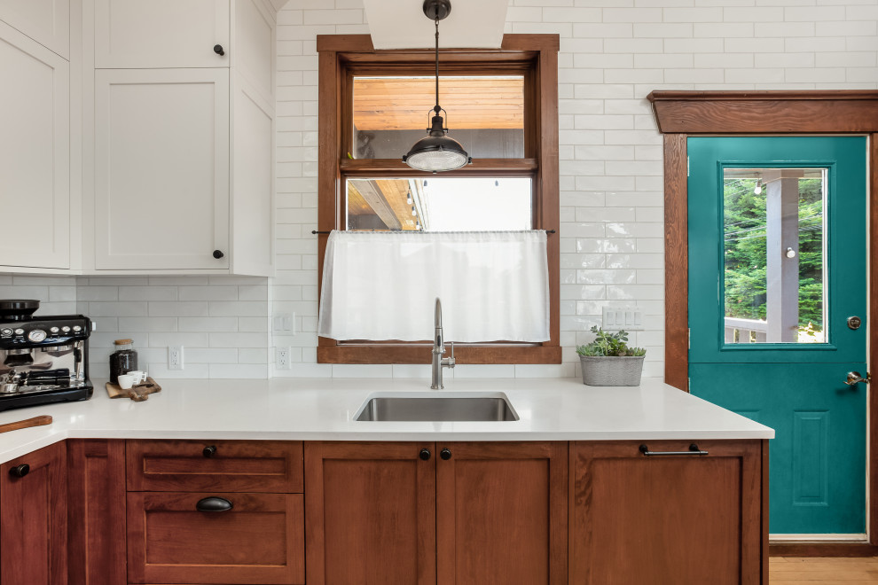 Example of a mid-sized mountain style u-shaped eat-in kitchen design in Vancouver with a peninsula, an undermount sink, shaker cabinets, white cabinets, quartz countertops, white backsplash, subway tile backsplash, stainless steel appliances and white countertops