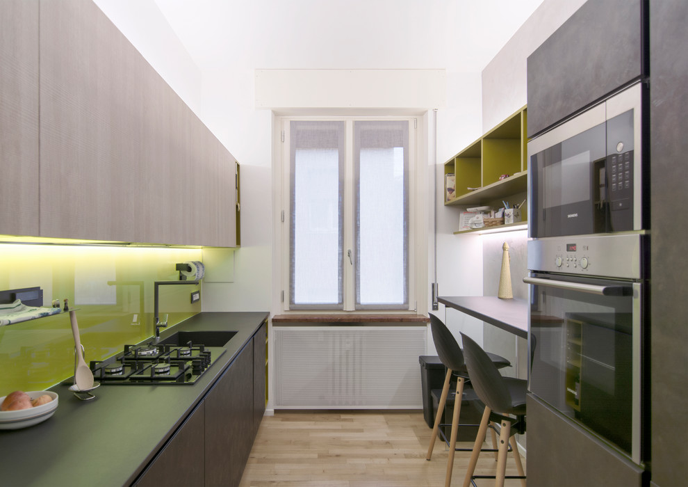 Inspiration for a mid-sized contemporary galley separate kitchen in Other with an integrated sink, flat-panel cabinets, black cabinets, quartzite benchtops, yellow splashback, glass sheet splashback, stainless steel appliances, light hardwood floors and no island.