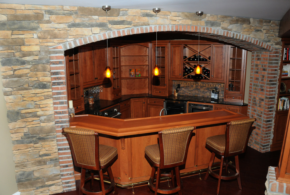Large traditional u-shaped seated home bar in Philadelphia with an undermount sink, recessed-panel cabinets, medium wood cabinets, solid surface benchtops and dark hardwood floors.
