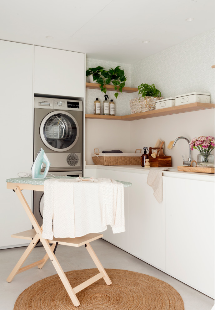 Foto på en stor vita l-formad tvättstuga enbart för tvätt, med en undermonterad diskho, släta luckor, vita skåp, klinkergolv i keramik, en tvättpelare och beiget golv