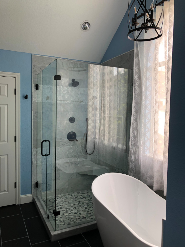 Inspiration for a medium sized contemporary ensuite bathroom in Dallas with shaker cabinets, a freestanding bath, a corner shower, a two-piece toilet, grey tiles, marble tiles, blue walls, ceramic flooring, a submerged sink, black floors, a hinged door, a shower bench, double sinks, a built in vanity unit and a vaulted ceiling.