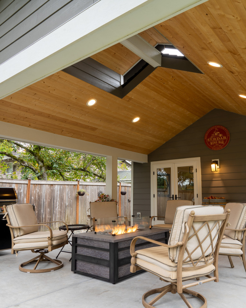 Idee per un patio o portico tradizionale dietro casa con un focolare, lastre di cemento e un tetto a sbalzo