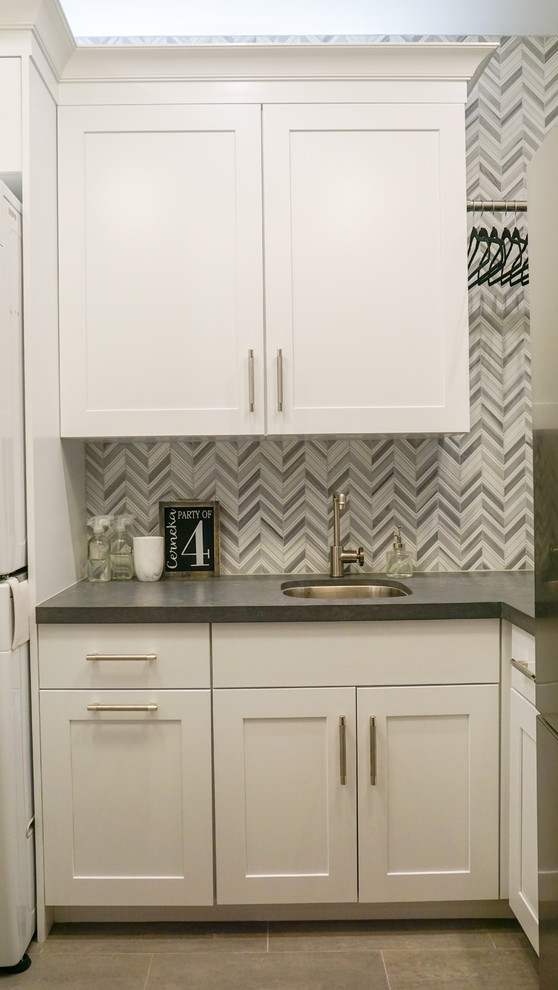 Inspiration for a small transitional l-shaped dedicated laundry room in Phoenix with an undermount sink, shaker cabinets, white cabinets, quartz benchtops, grey walls, porcelain floors, a stacked washer and dryer, grey floor and grey benchtop.