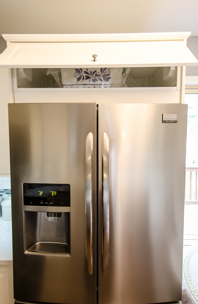 Enclosed kitchen - mid-sized transitional l-shaped vinyl floor enclosed kitchen idea in DC Metro with an undermount sink, shaker cabinets, quartz countertops, white backsplash, ceramic backsplash, black appliances and no island