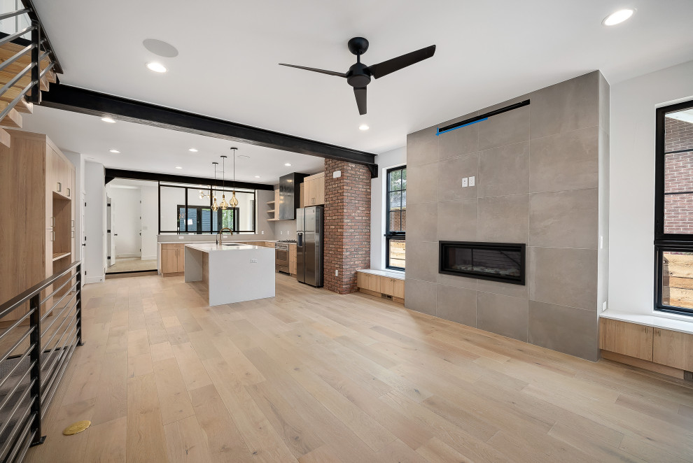 Inspiration for a small industrial open concept light wood floor, brown floor, exposed beam and brick wall family room remodel in Denver with white walls, a standard fireplace and a tile fireplace