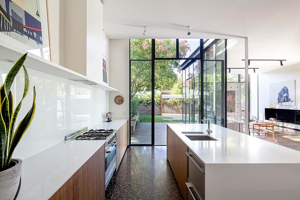 Photo of a large contemporary single-wall open plan kitchen in London with a double-bowl sink, flat-panel cabinets, medium wood cabinets, white splashback, stainless steel appliances, an island, composite countertops and glass sheet splashback.
