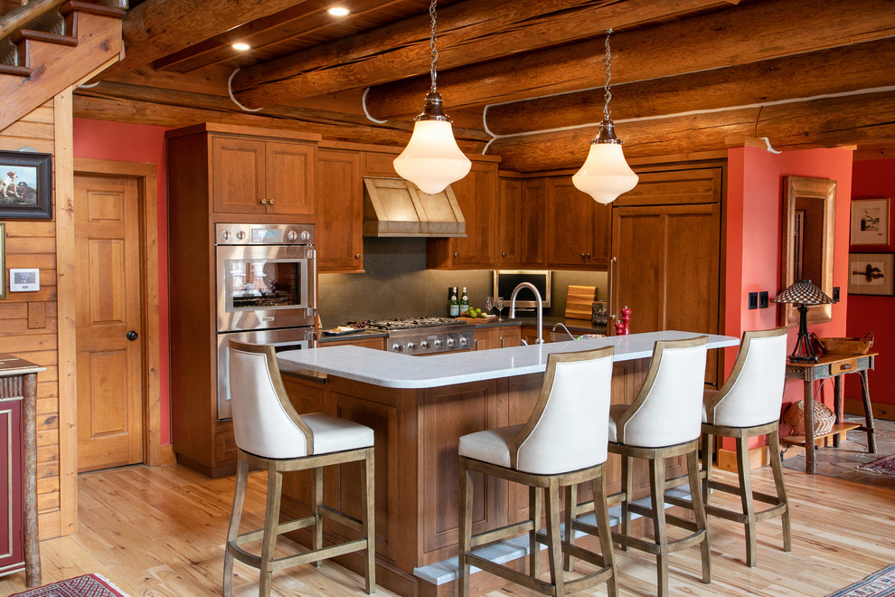Mid-sized mountain style l-shaped light wood floor open concept kitchen photo in Milwaukee with recessed-panel cabinets, medium tone wood cabinets, quartz countertops, gray backsplash, stone slab backsplash, stainless steel appliances, gray countertops and an island