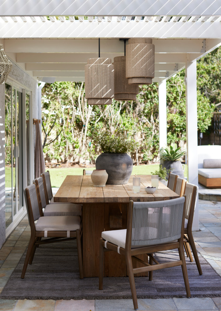 Example of a beach style backyard tile patio design in Los Angeles with a pergola