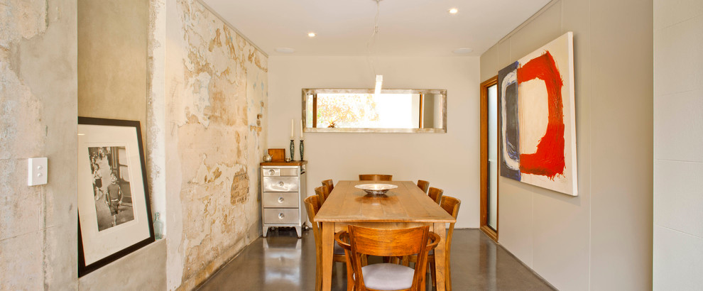 Photo of a mid-sized mediterranean kitchen/dining combo in Sydney with white walls, concrete floors and no fireplace.