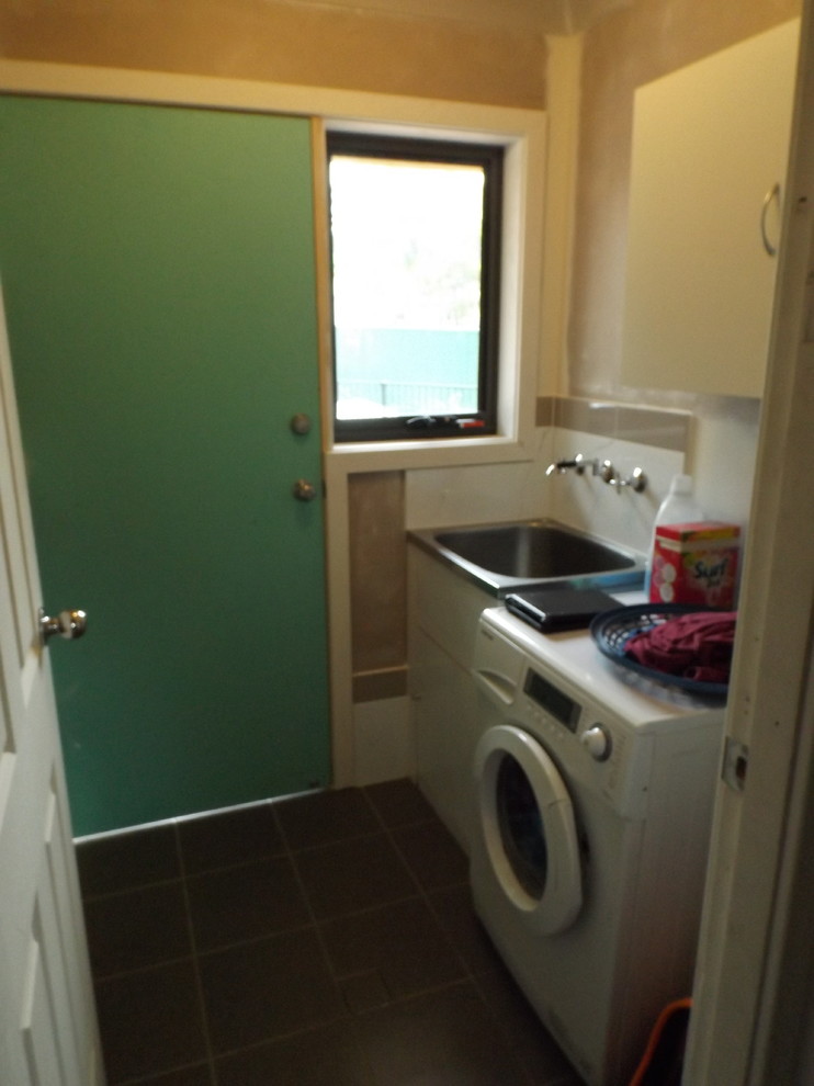 This is an example of a small modern galley dedicated laundry room in Sydney with a single-bowl sink, white walls and ceramic floors.