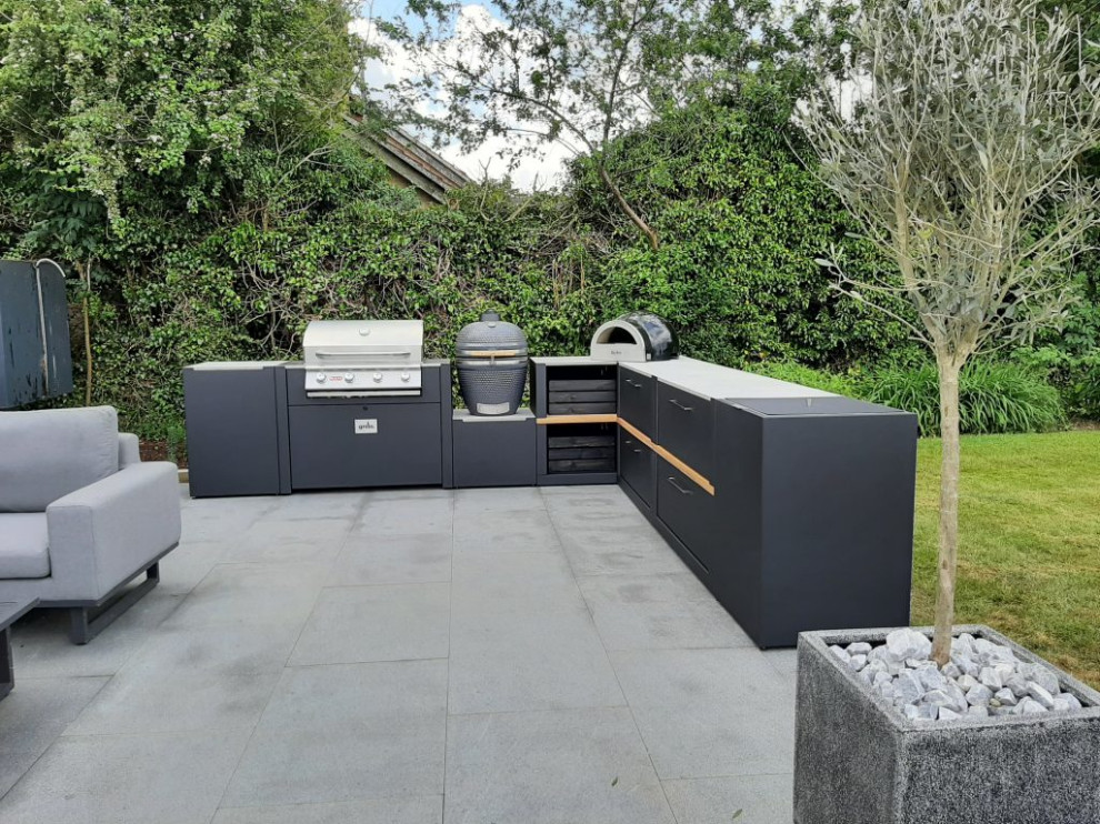 Cette photo montre une grande terrasse arrière tendance avec une cuisine d'été, des pavés en pierre naturelle et aucune couverture.