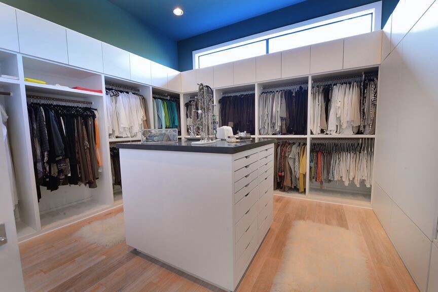 Design ideas for a mid-sized modern gender-neutral walk-in wardrobe in Houston with flat-panel cabinets, white cabinets and bamboo floors.