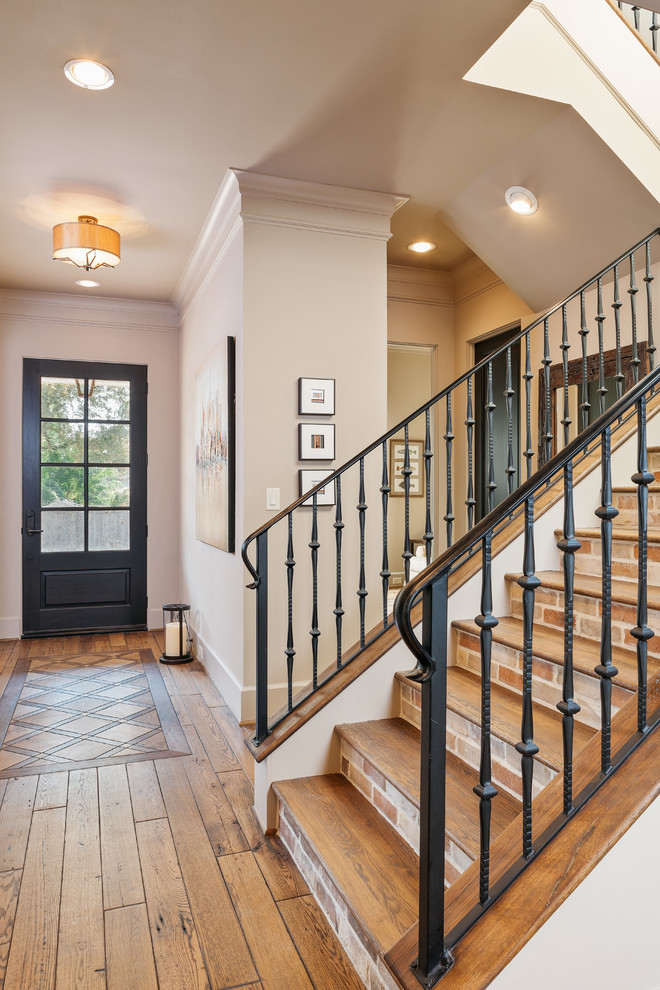 Photo of an expansive industrial wood u-shaped staircase in Houston with tile risers and metal railing.