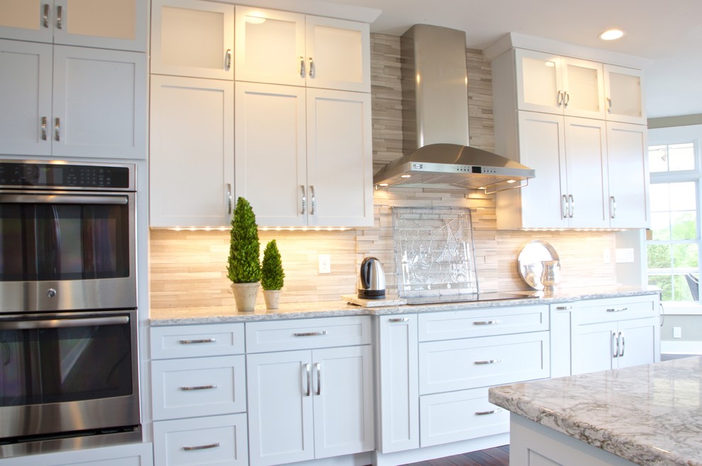 Eat-in kitchen - mid-sized transitional galley eat-in kitchen idea with white cabinets, granite countertops, beige backsplash, stone tile backsplash and stainless steel appliances