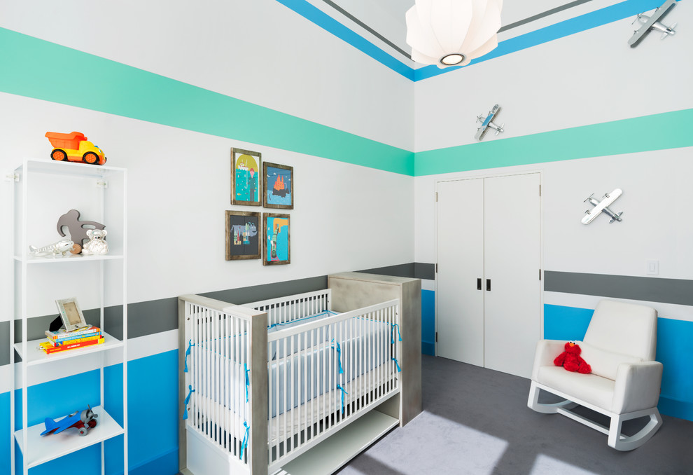 Design ideas for a mid-sized contemporary nursery for boys in New York with carpet, multi-coloured walls and grey floor.