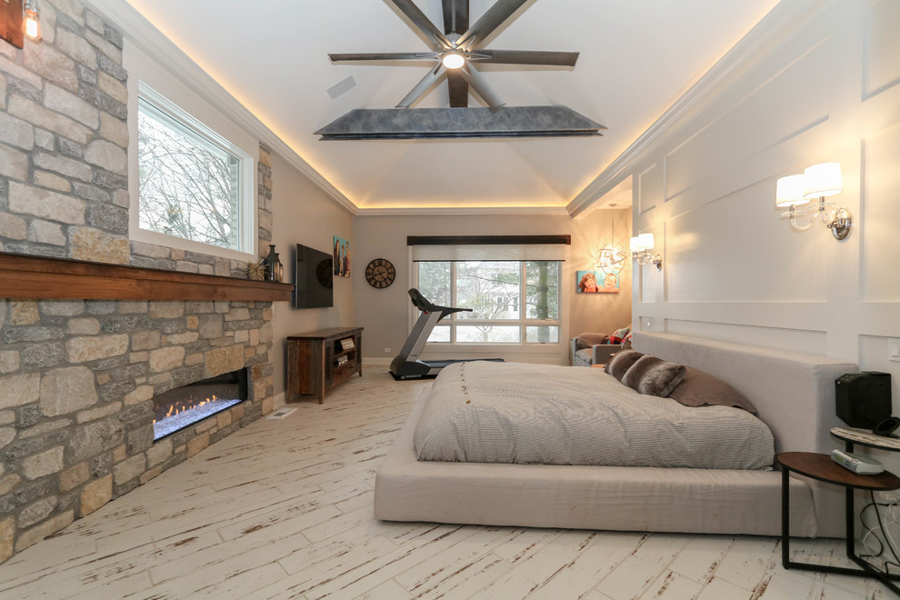 This is an example of a large industrial master bedroom in Chicago with beige walls, ceramic floors, a standard fireplace, a stone fireplace surround and beige floor.
