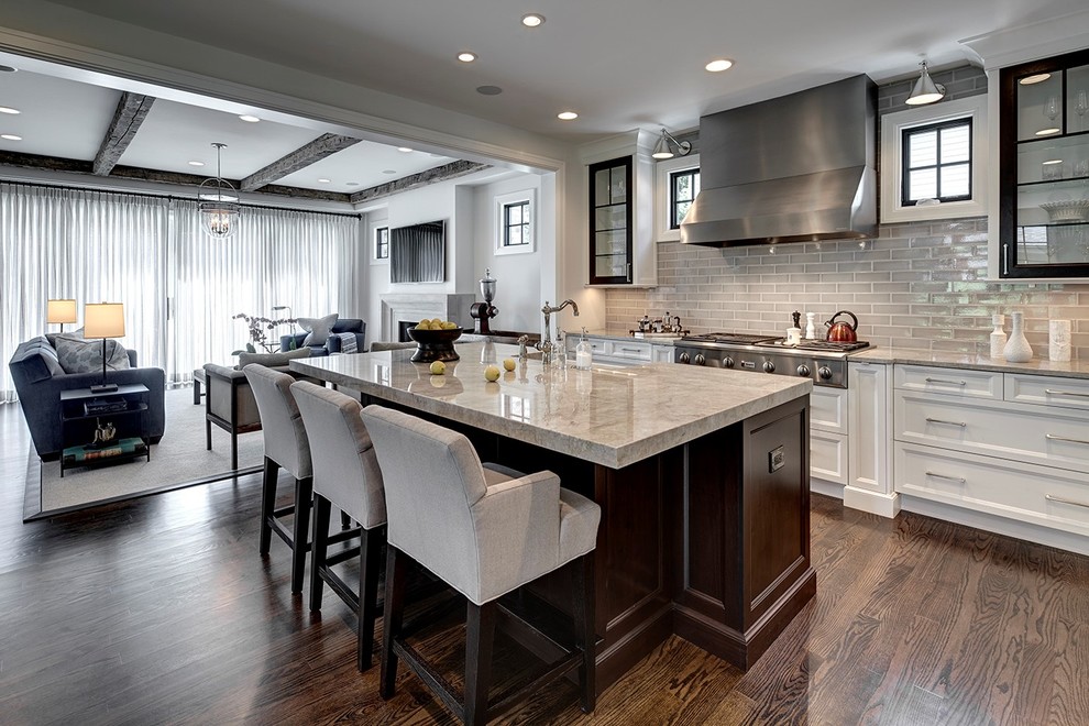 Transitional galley open plan kitchen in Detroit with recessed-panel cabinets, white cabinets, grey splashback, subway tile splashback, stainless steel appliances, with island and dark hardwood floors.