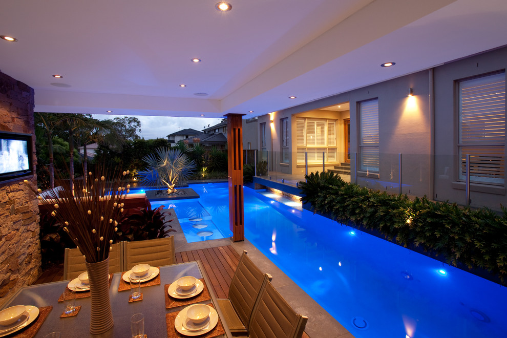 Design ideas for a mid-sized modern backyard custom-shaped pool in Sydney with a pool house and decking.