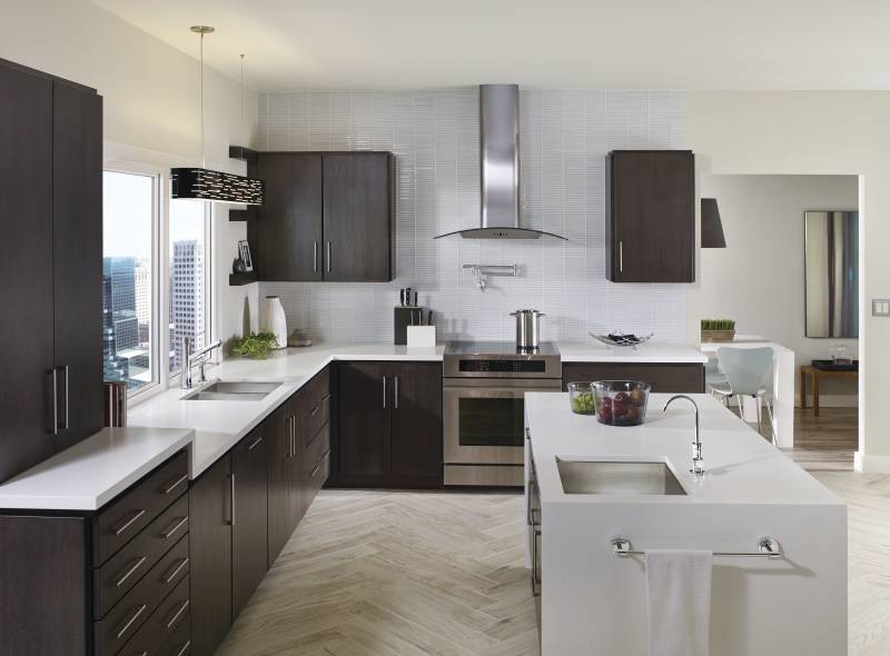 Photo of a mid-sized modern l-shaped kitchen in Cleveland with flat-panel cabinets, black cabinets, with island, an undermount sink, laminate benchtops, white splashback, glass tile splashback, stainless steel appliances and light hardwood floors.