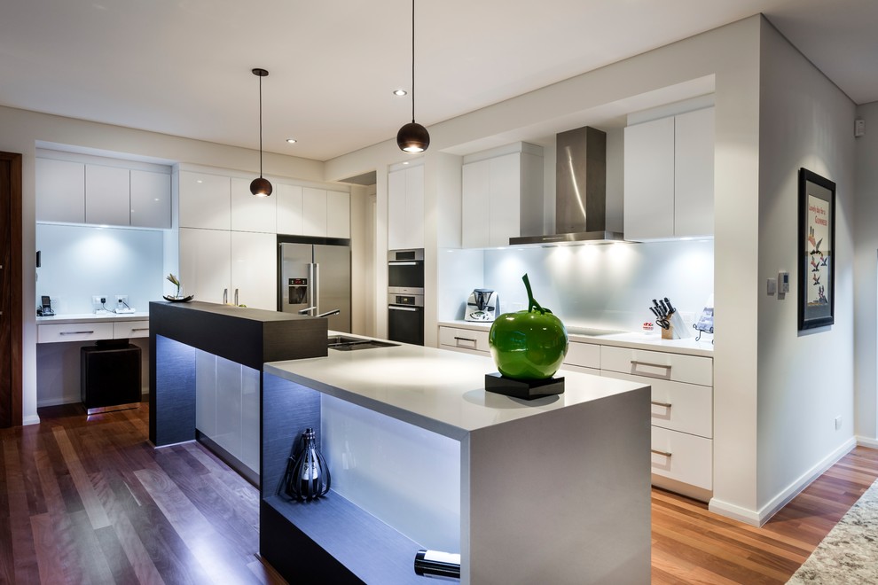 Design ideas for a mid-sized contemporary u-shaped eat-in kitchen in Perth with a double-bowl sink, white cabinets, quartz benchtops, white splashback, glass sheet splashback, stainless steel appliances, medium hardwood floors, with island, brown floor, white benchtop and flat-panel cabinets.