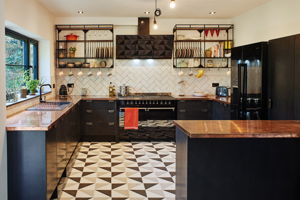 Photo of a mid-sized modern u-shaped eat-in kitchen in Sussex with a drop-in sink, flat-panel cabinets, black cabinets, copper benchtops, white splashback, subway tile splashback, black appliances, ceramic floors, a peninsula and multi-coloured floor.