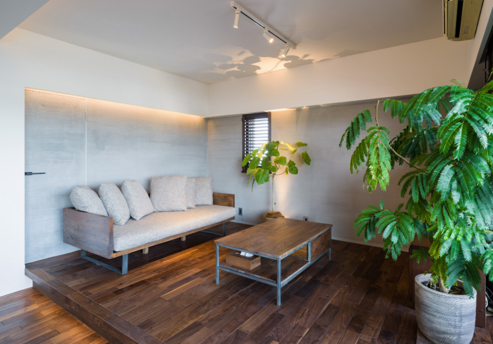 Asiatisches Wohnzimmer mit grauer Wandfarbe, dunklem Holzboden und braunem Boden in Sonstige