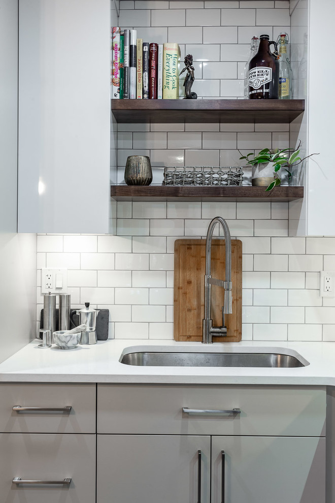 Small contemporary l-shaped kitchen in Vancouver with an undermount sink, flat-panel cabinets, grey cabinets, quartz benchtops, white splashback, subway tile splashback, stainless steel appliances, cement tiles, with island, grey floor and white benchtop.