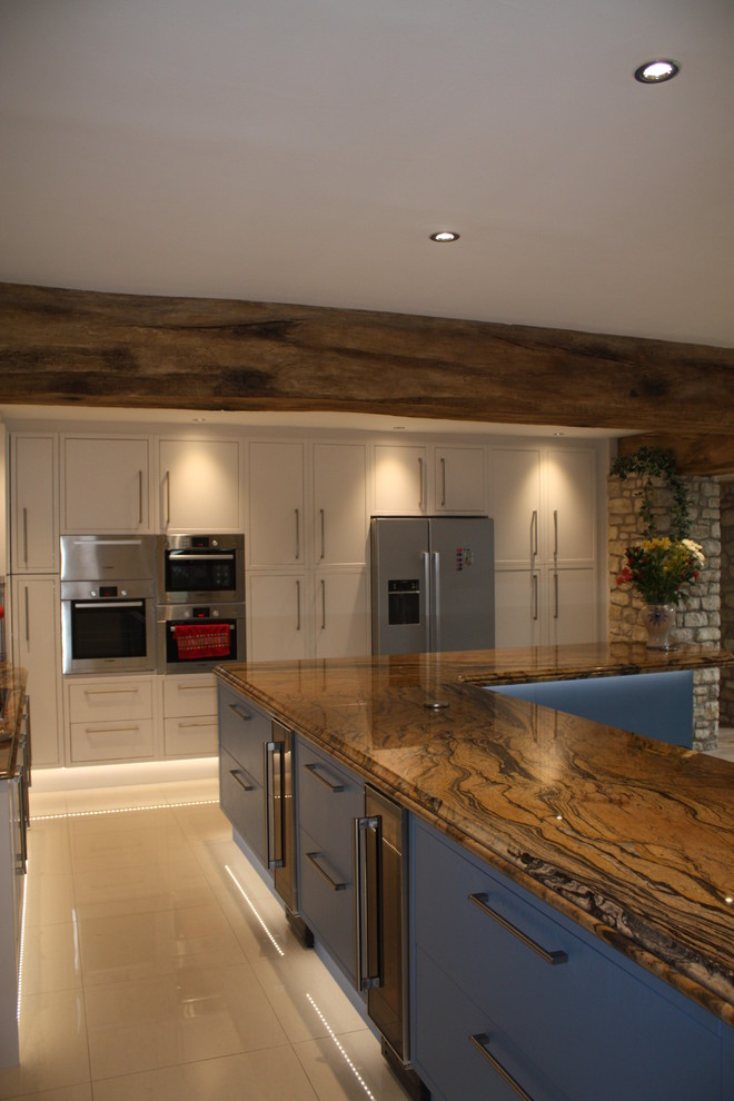 Design ideas for a large contemporary l-shaped kitchen/diner with a belfast sink, flat-panel cabinets, blue cabinets, granite worktops, stainless steel appliances, travertine flooring and an island.