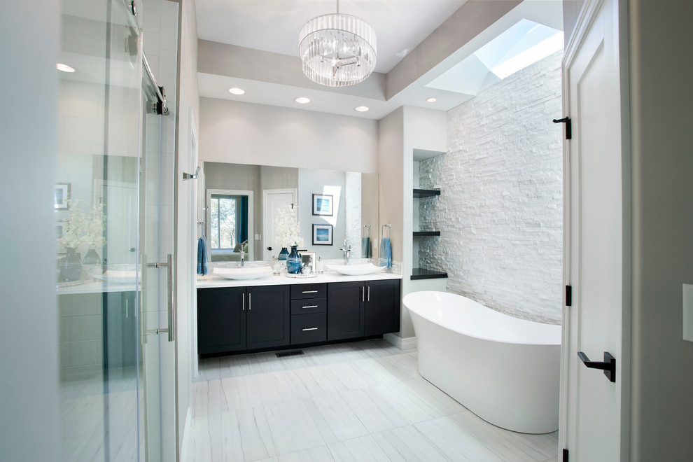 Inspiration for a large transitional master white tile and porcelain tile porcelain tile freestanding bathtub remodel in Wichita with shaker cabinets, black cabinets, gray walls, a vessel sink and quartz countertops